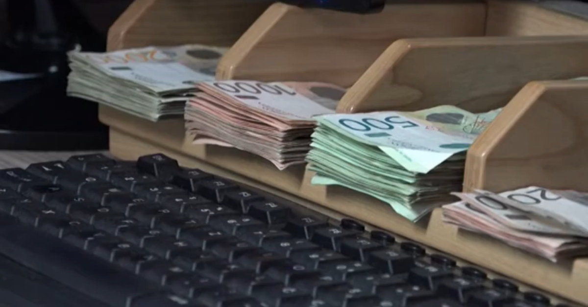 Poređene novčanice različitih apoena na pultu menjačnice, uz tastaturu ispred njih