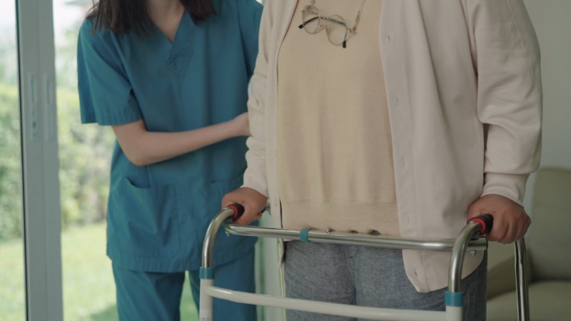 Medicinska radnica pomaže starijoj osobi koja se oslanja na hodalicu